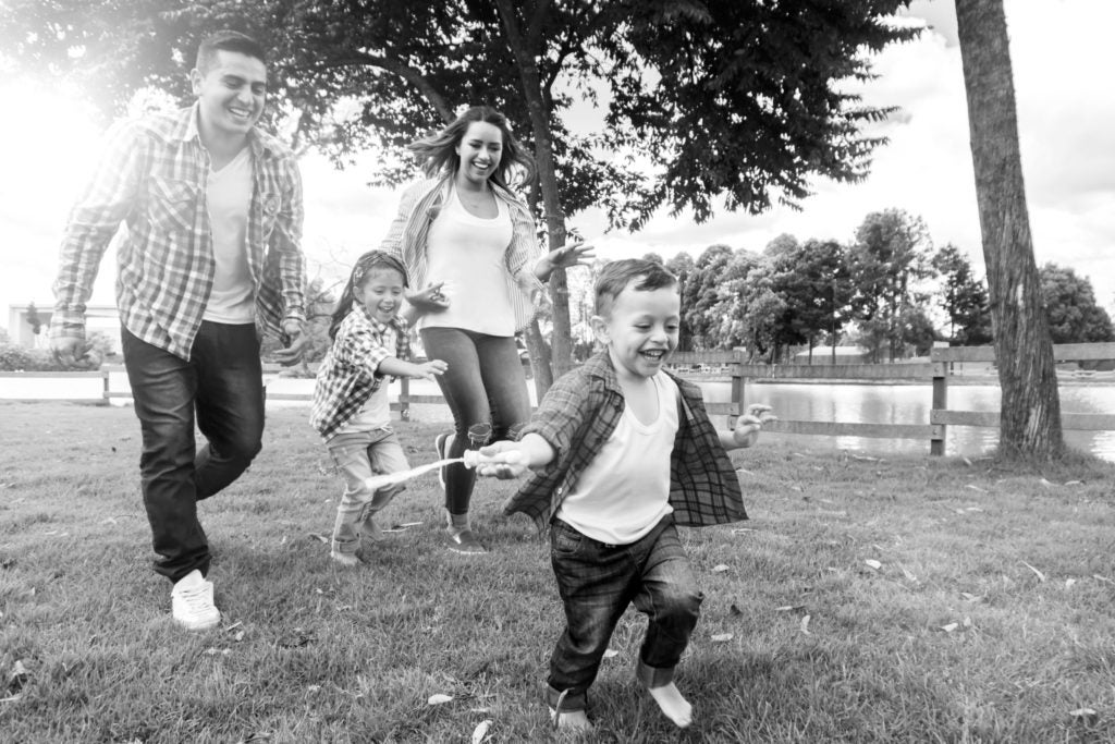 Family of four running and playing in the park