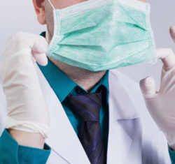 A dentist putting on protective gear against infection