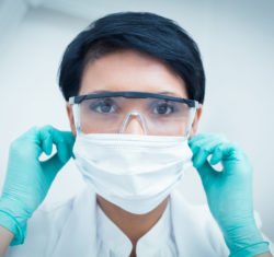 Dental hygienist wearing a mask, eye protection, and gloves