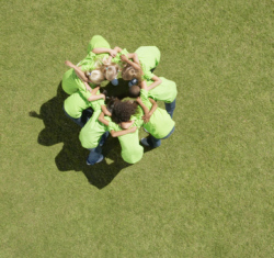 Image of a team of children huddled together on a grass field