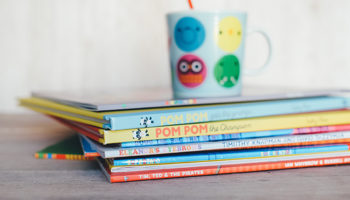 A stack of kids books and a mug