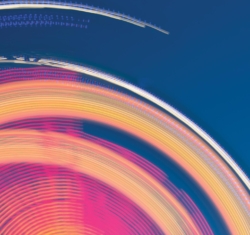 Bright colors of pink, yellow, and white spin as if they're caught mid-motion emphasizing something moving at a fast speed, almost out of control. The deep blue, calming background further emphasizes the velocity of the spinning.