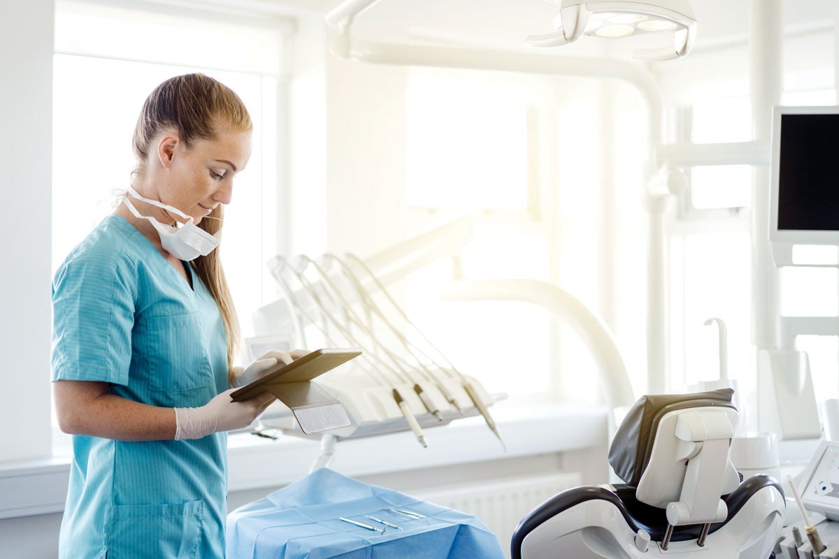 A hygienist takes notes in an empty operatory after running a water line test. 