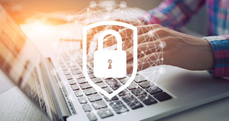 Cyber security depicted through a man's hands on a keyboard of a laptop. In the photo we see the sleeves of his red and blue plaid shirt. Superimposed over the image are graphics symbolizing the interconnectedness of our world behind a bold lock in a shield.