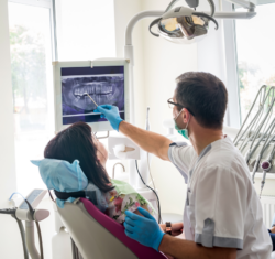 Reducing patient cancellations starts with the hygienist identifying specific reasons for the next hygiene visit. Shown in this image, a hygienist is utilizing a 3d xray of a patient's mouth to build specific, patient-focused reasons to return.